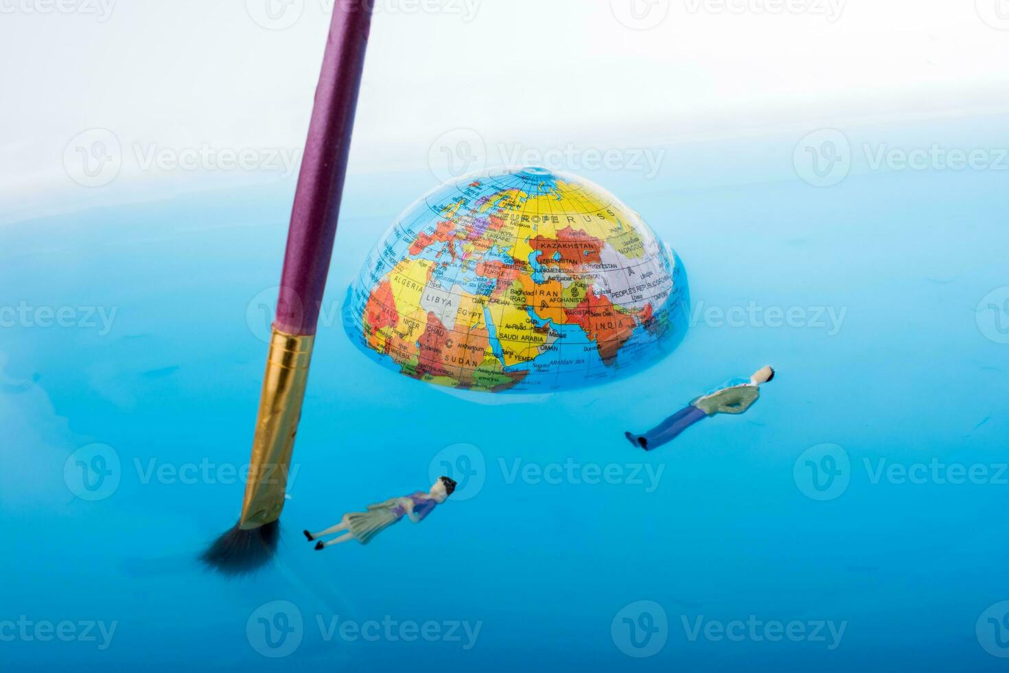 Bürste und kleiner Globus mit schwebenden Figuren foto
