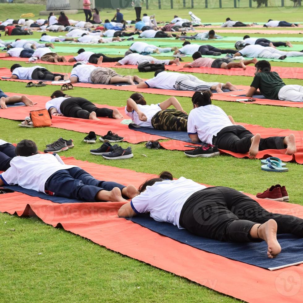 Gruppen-Yoga-Übungssitzung für Menschen verschiedener Altersgruppen im Cricket-Stadion in Delhi am internationalen Yoga-Tag, große Gruppe von Erwachsenen, die an Yoga-Sitzungen teilnehmen foto