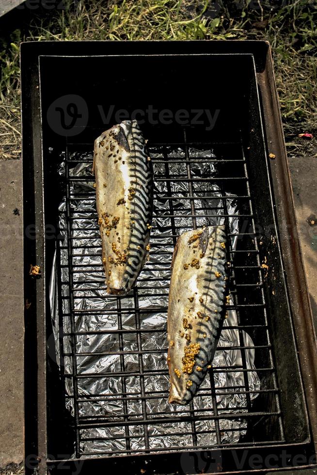 Makrelenfisch in einer Marinade auf einem Grill in einer Räucherei. der Prozess des Kochens von heiß geräucherter Makrele foto