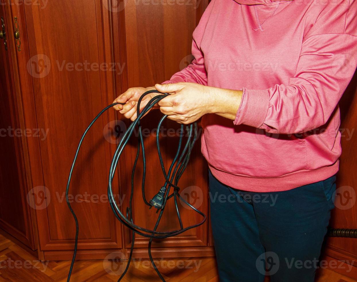 Frauenhände halten ein elektrisches Kabel. schwarzes Kabel, Elektronik. foto