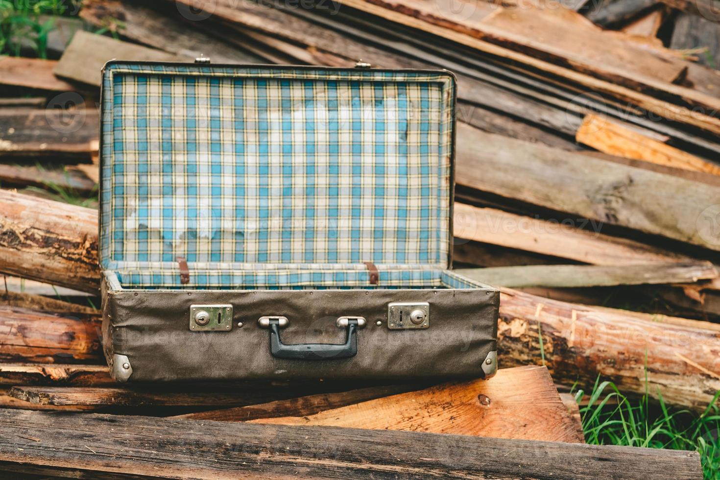 alter leerer Koffer auf Holzstöcken, vor dem Hintergrund eines kaputten Hauses foto