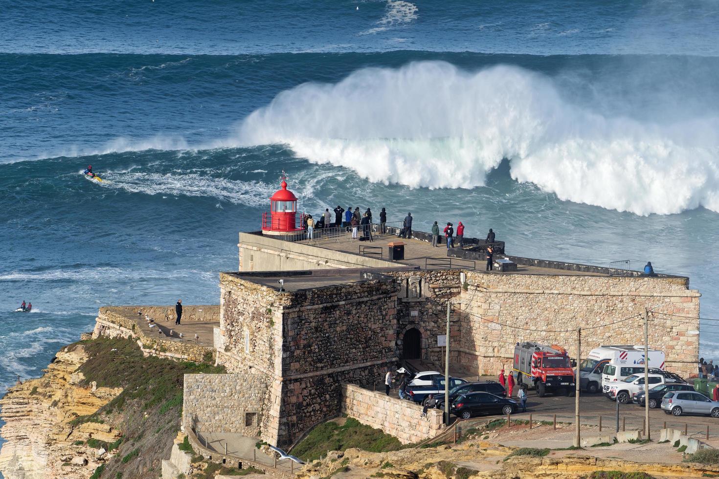 nazare, portugal - 7. november 2022 leute beobachten die großen riesigen wellen, die in der nähe des forts des leuchtturms von nazare in nazare, portugal, zusammenbrechen. größten wellen der welt. touristisches Ziel zum Surfen. foto
