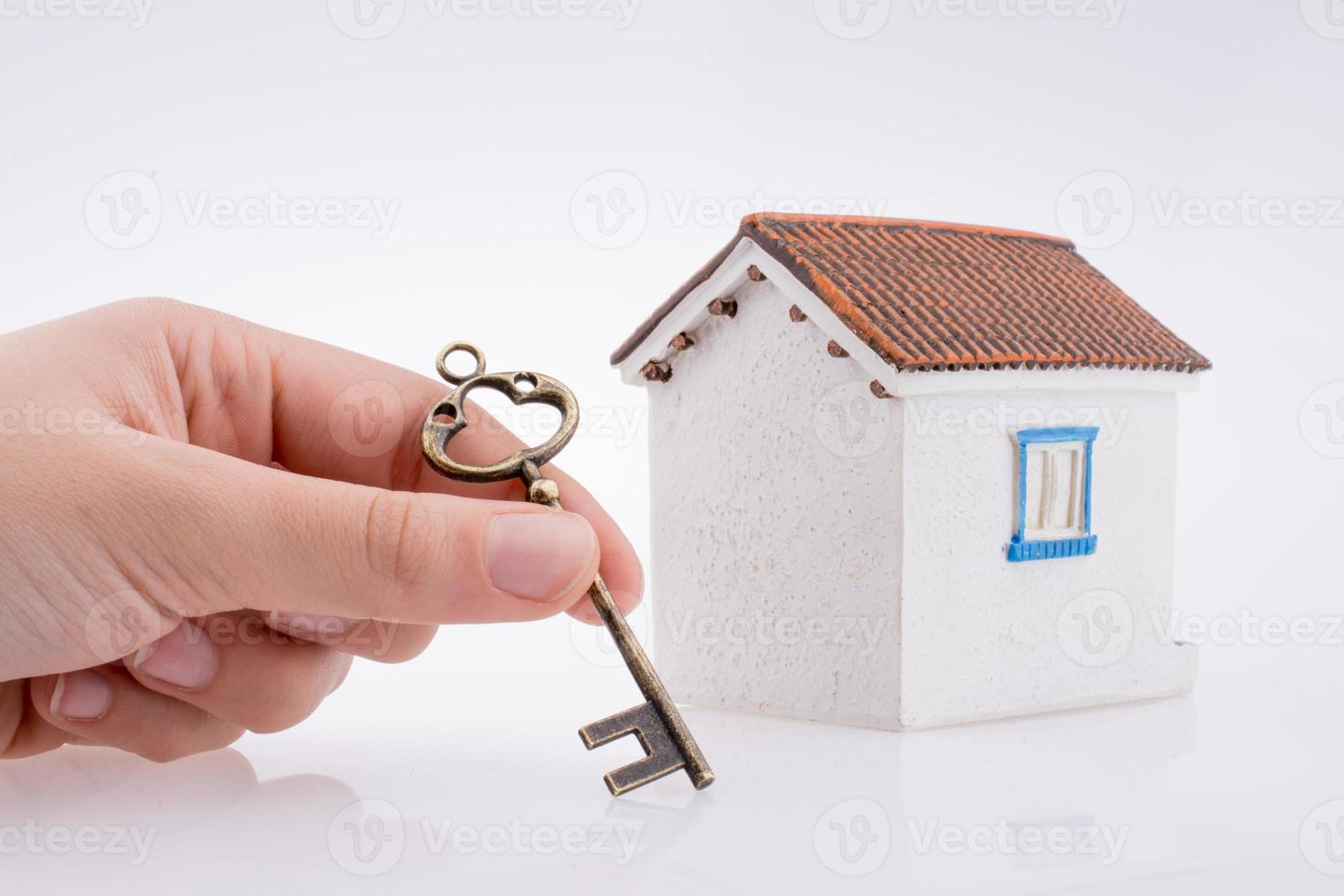 Hand, die einen Schlüssel in der Nähe eines Hauses hält foto
