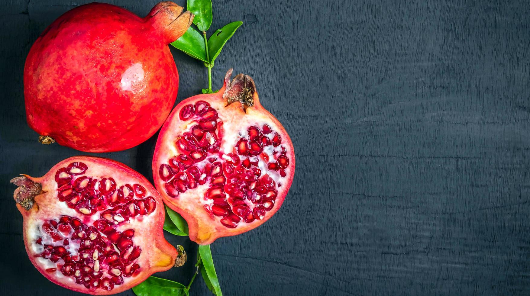 Draufsicht auf halbreifen Granatapfel und offenen roten Granatapfel mit Granatapfelblättern foto