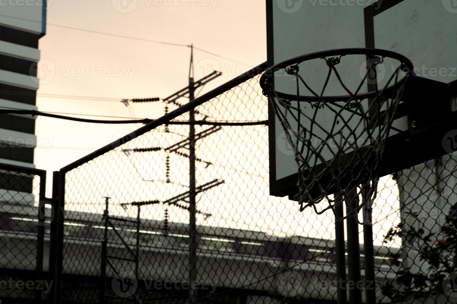 Blick aus der Vogelperspektive auf den alten Basketballkorb mit bewegungsunscharfem Zug im Hintergrund des Dämmerungshimmels foto