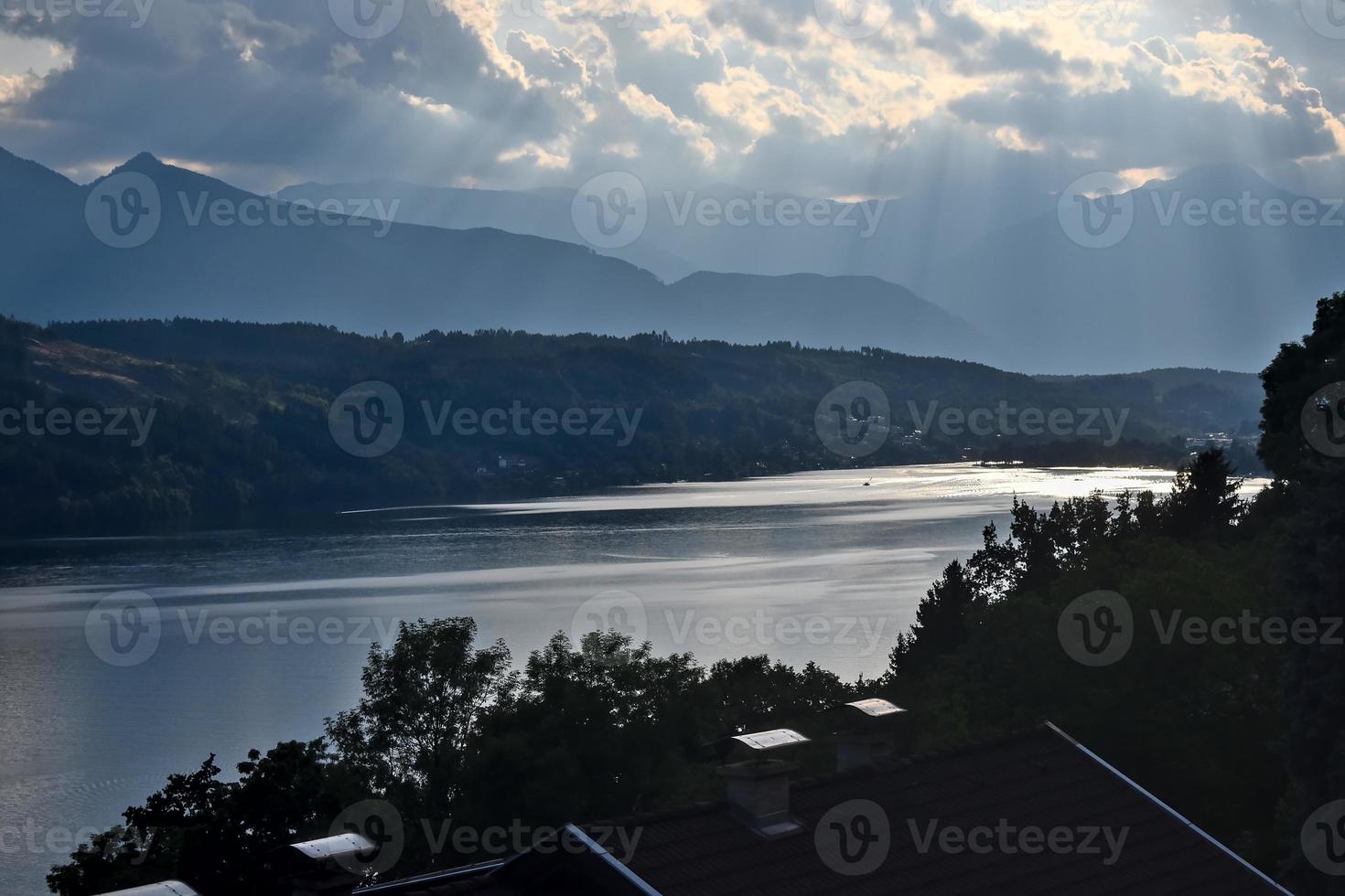 Sonnenschein berührt das Wasser des Millstätter Sees in Österreich mit Bergen der Alpen im Hintergrund. malerische Landschaft an einem bewölkten Tag foto