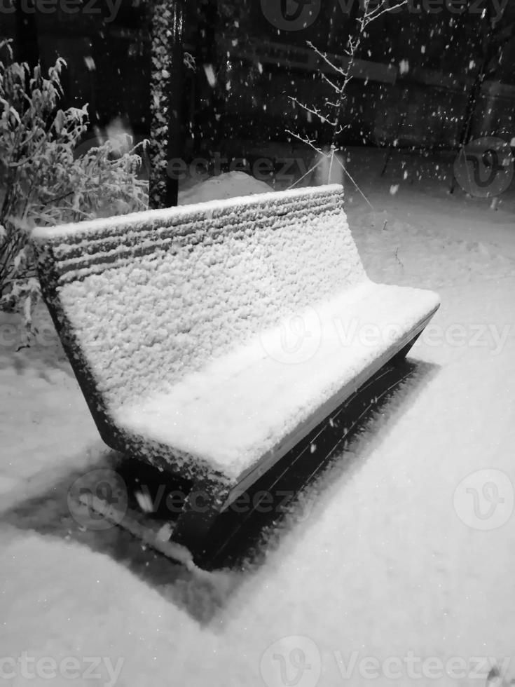 verschneiter Tag im Park. Holzbank im Schnee an einem verschneiten Abend. Schneefall im Erholungspark. foto