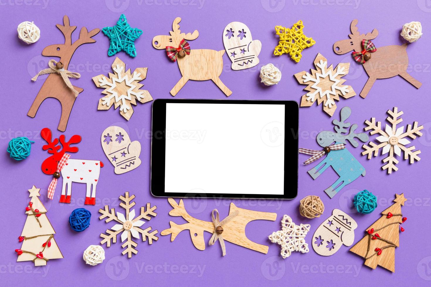 festliche dekorationen und spielzeug auf lila hintergrund. Draufsicht des digitalen Tablets. Frohe Weihnachten-Konzept foto