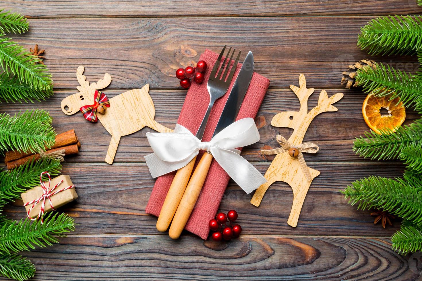 Draufsicht auf Utensilien auf festlicher Serviette auf Holzgrund. weihnachtsschmuck mit getrockneten früchten und zimt. nahaufnahme des neujahrsdinnerkonzepts foto