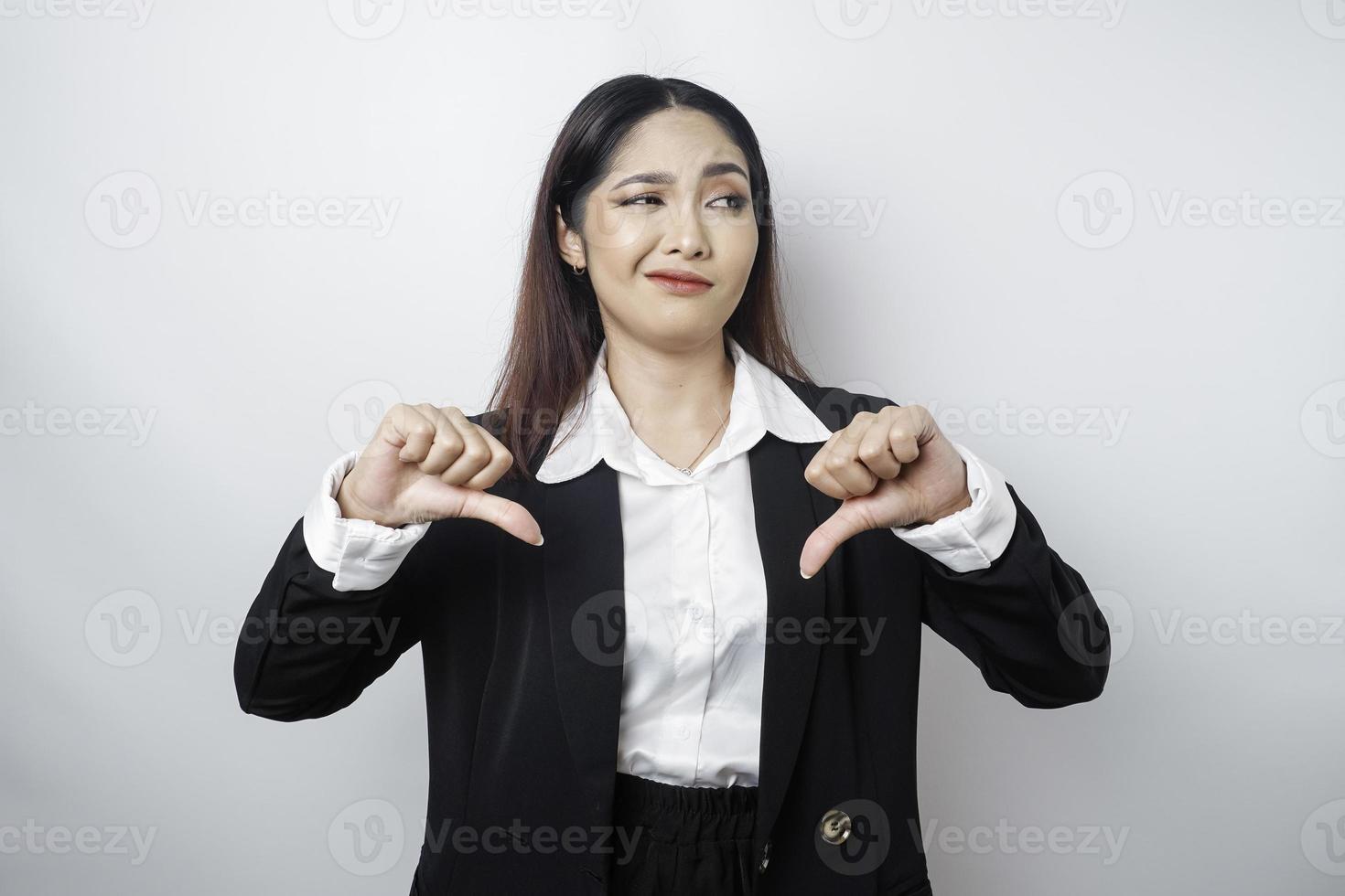 enttäuschte asiatische Geschäftsfrau gibt Daumen nach unten Handgeste der Missbilligung, isoliert durch einen weißen Hintergrund foto