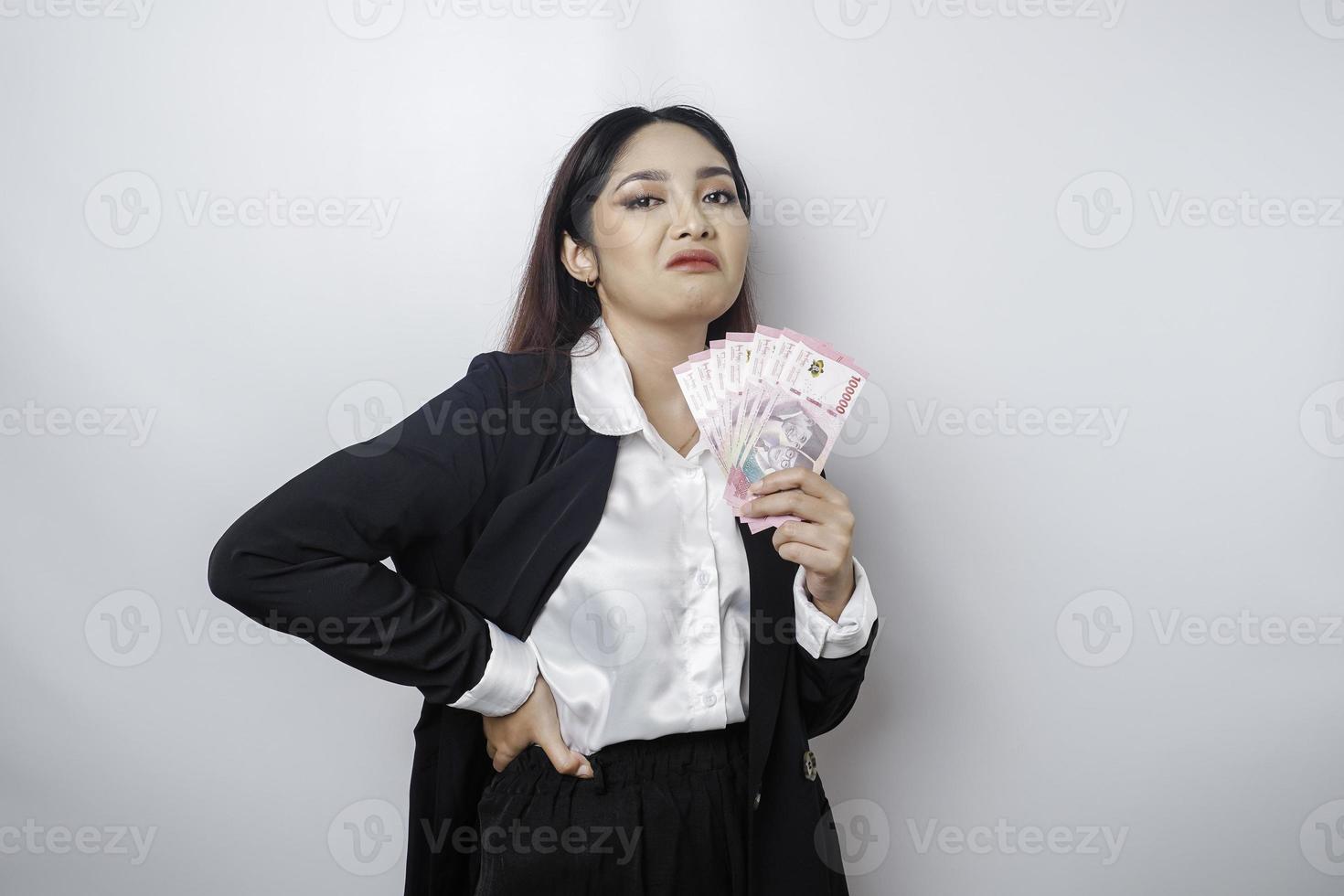 ein Porträt, wenn eine junge Geschäftsfrau mit einem Stapel Geld in indonesischen Rupiah in ihren Händen durch weißen Hintergrund isoliert foto