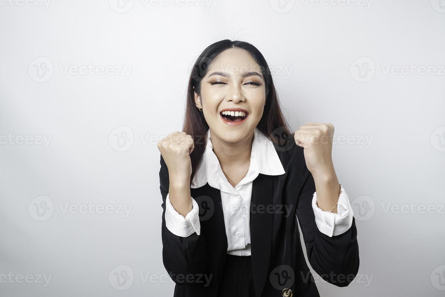 eine junge asiatische geschäftsfrau mit einem glücklichen erfolgreichen ausdruck, der schwarzen anzug trägt, der durch weißen hintergrund getrennt wird foto