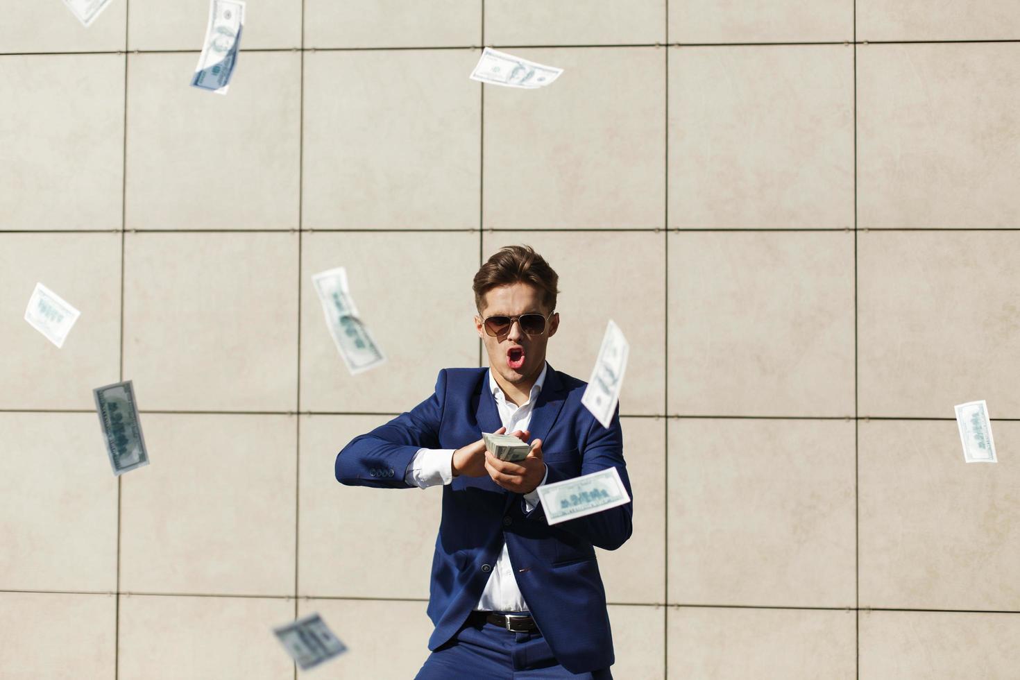 junger Geschäftsmann geht durch Dollars und tanzt auf der Straße foto