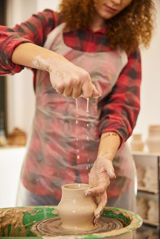 Frau streut Wasser auf eine Keramikware foto