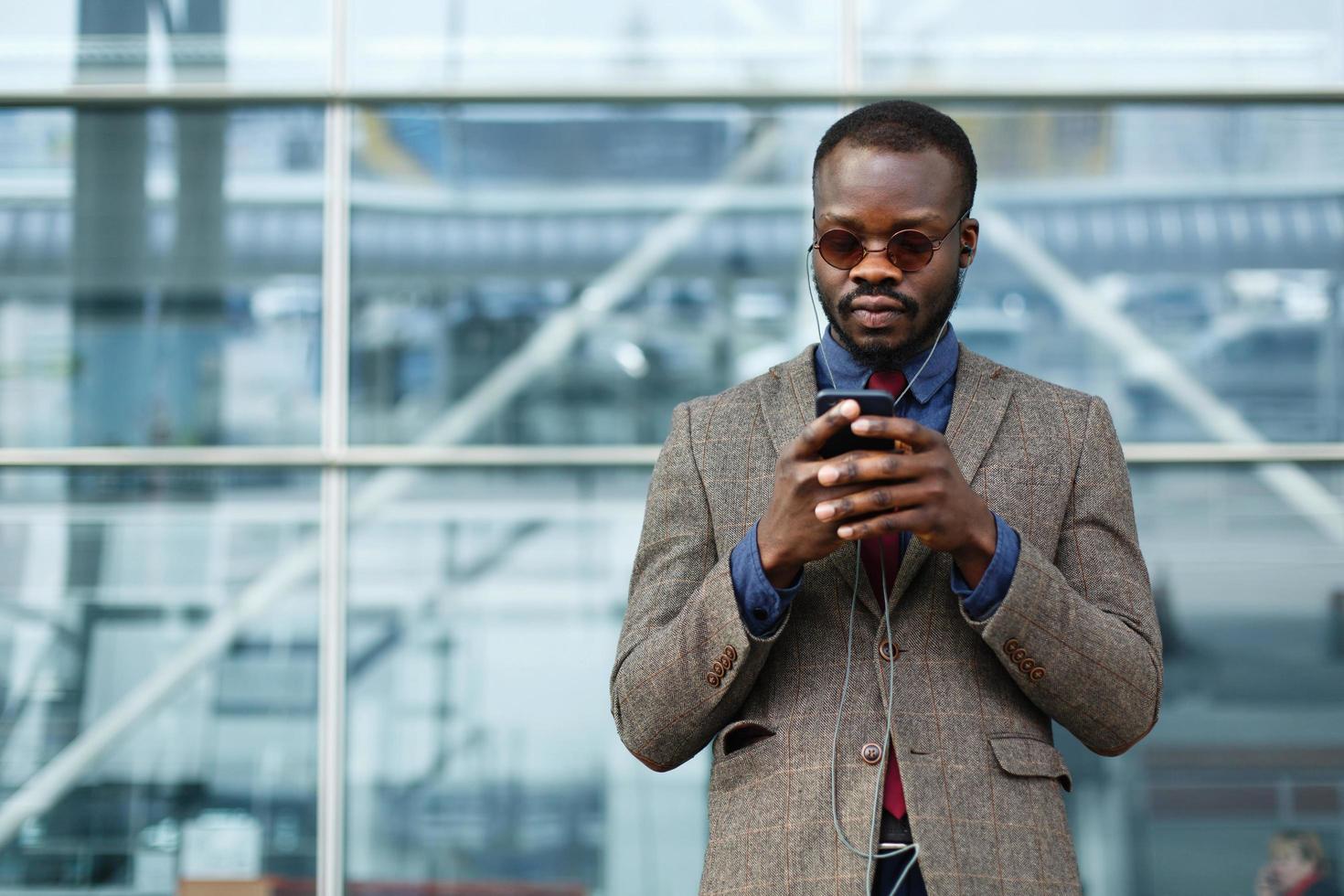 stilvoller Afroamerikaner schwarzer Geschäftsmann arbeitet auf seinem Smartphone foto