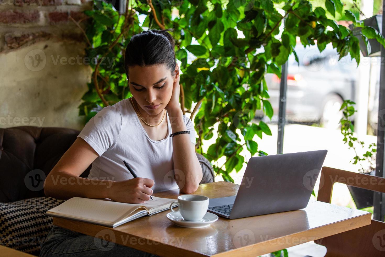 Junge Geschäftsfrau arbeitet in ihrer Pause in einer Cafeteria. Frau macht eine Pause. Spaß an der Arbeit im Café. Geschäfte vom Café aus tätigen foto