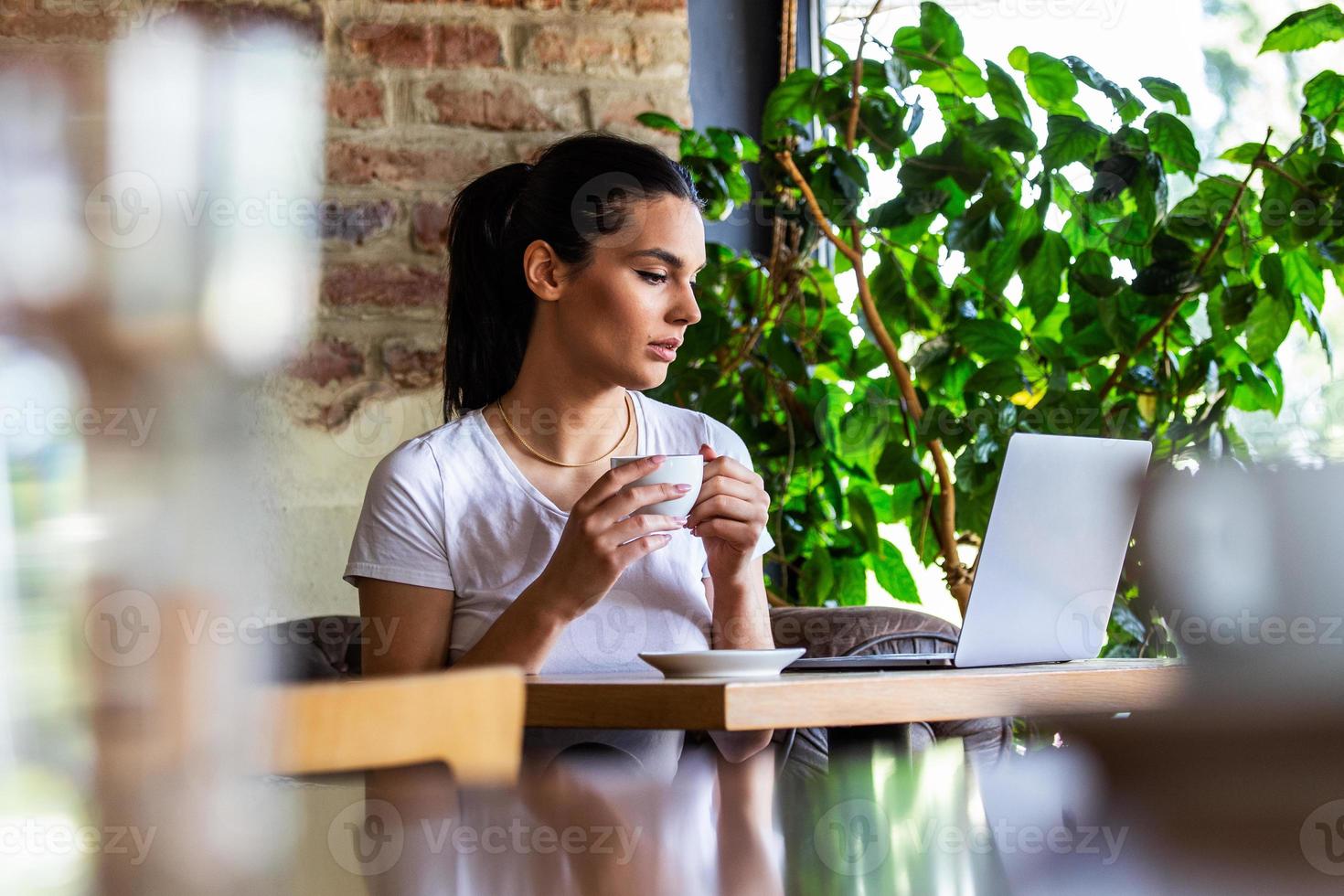 Junge Geschäftsfrau arbeitet in ihrer Pause in einer Cafeteria. Frau macht eine Pause. Spaß an der Arbeit im Café. Geschäfte vom Café aus tätigen foto