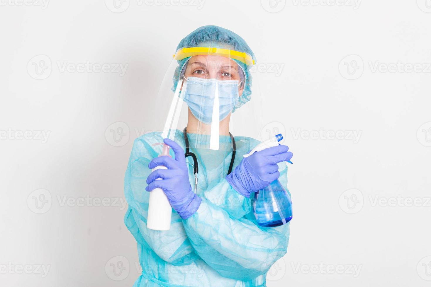 frau mit handschuhen, schutzanzug für biogefährdungen, gesichtsschutz und maske mit händedesinfektionsflasche und desinfektionsgel. Corona-Virus oder Covid-19-Schutz. foto