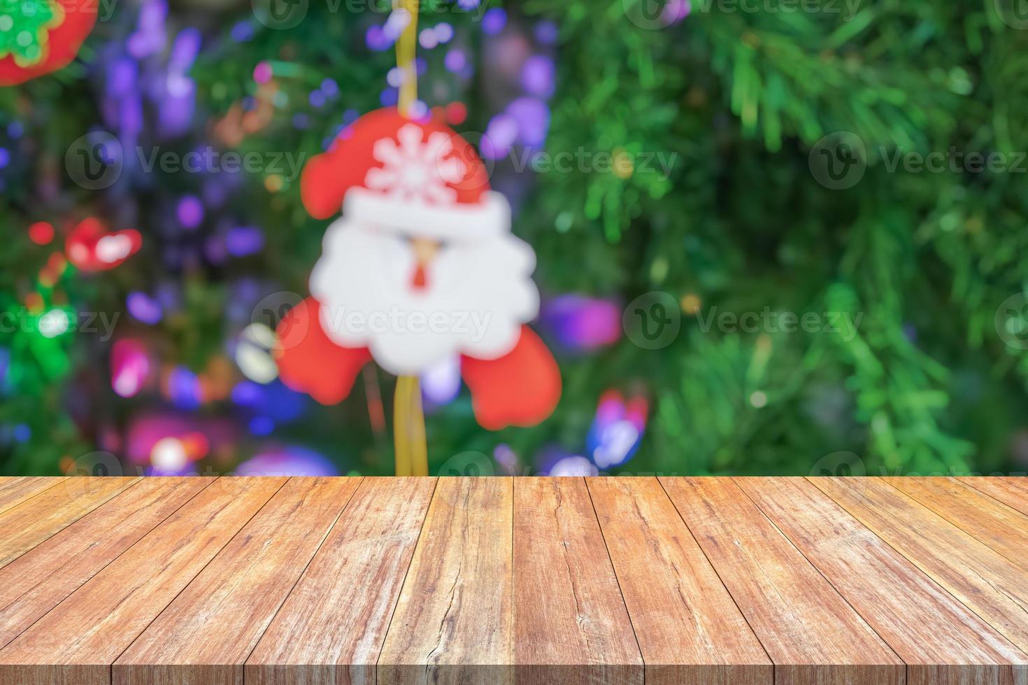 leere hölzerne tischplatte mit unscharfem weihnachtsbaum mit bokeh hellem hintergrund foto