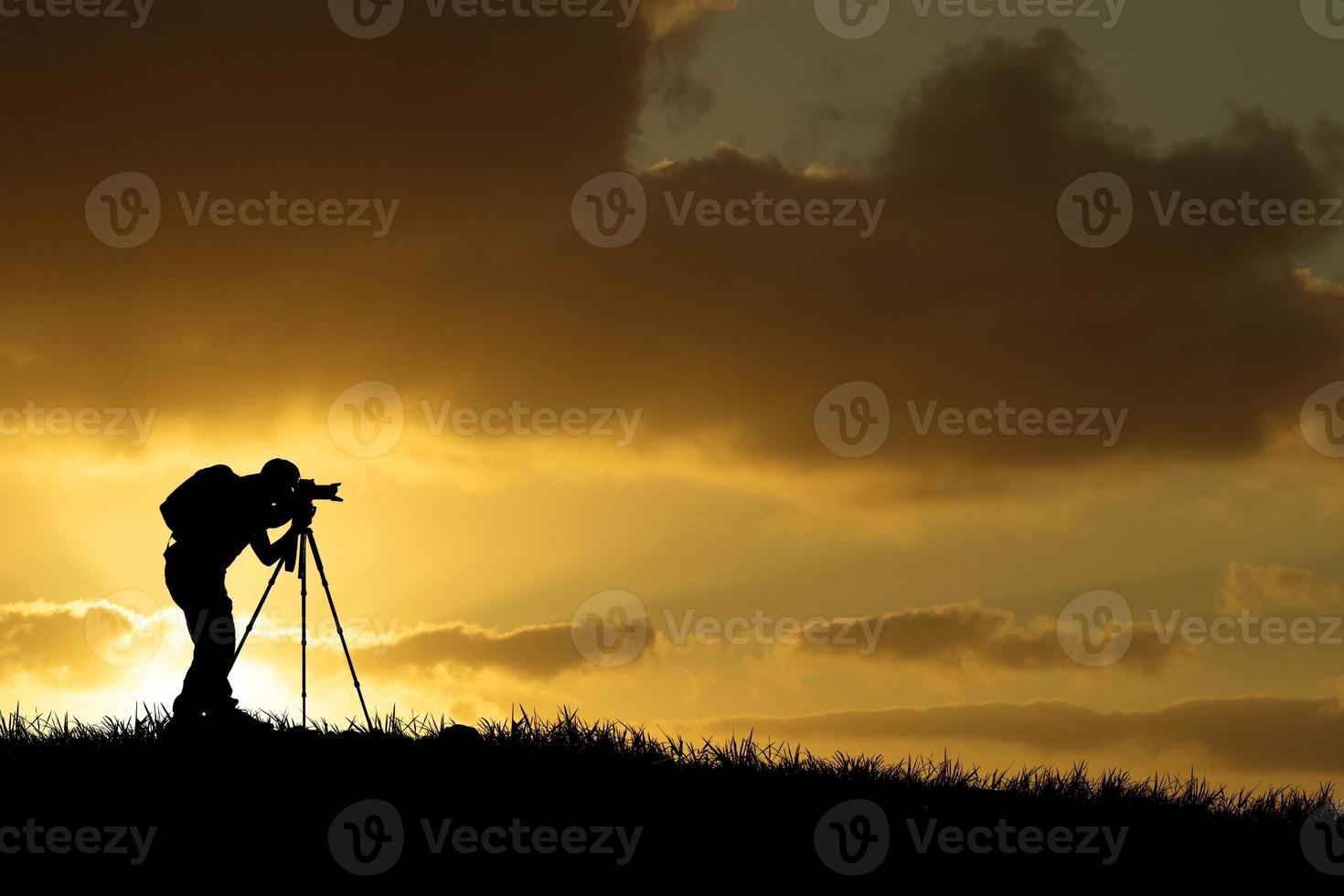 Die Silhouette eines professionellen Fotografen konzentriert sich auf das Fotografieren auf einer wunderschönen Wiese. foto