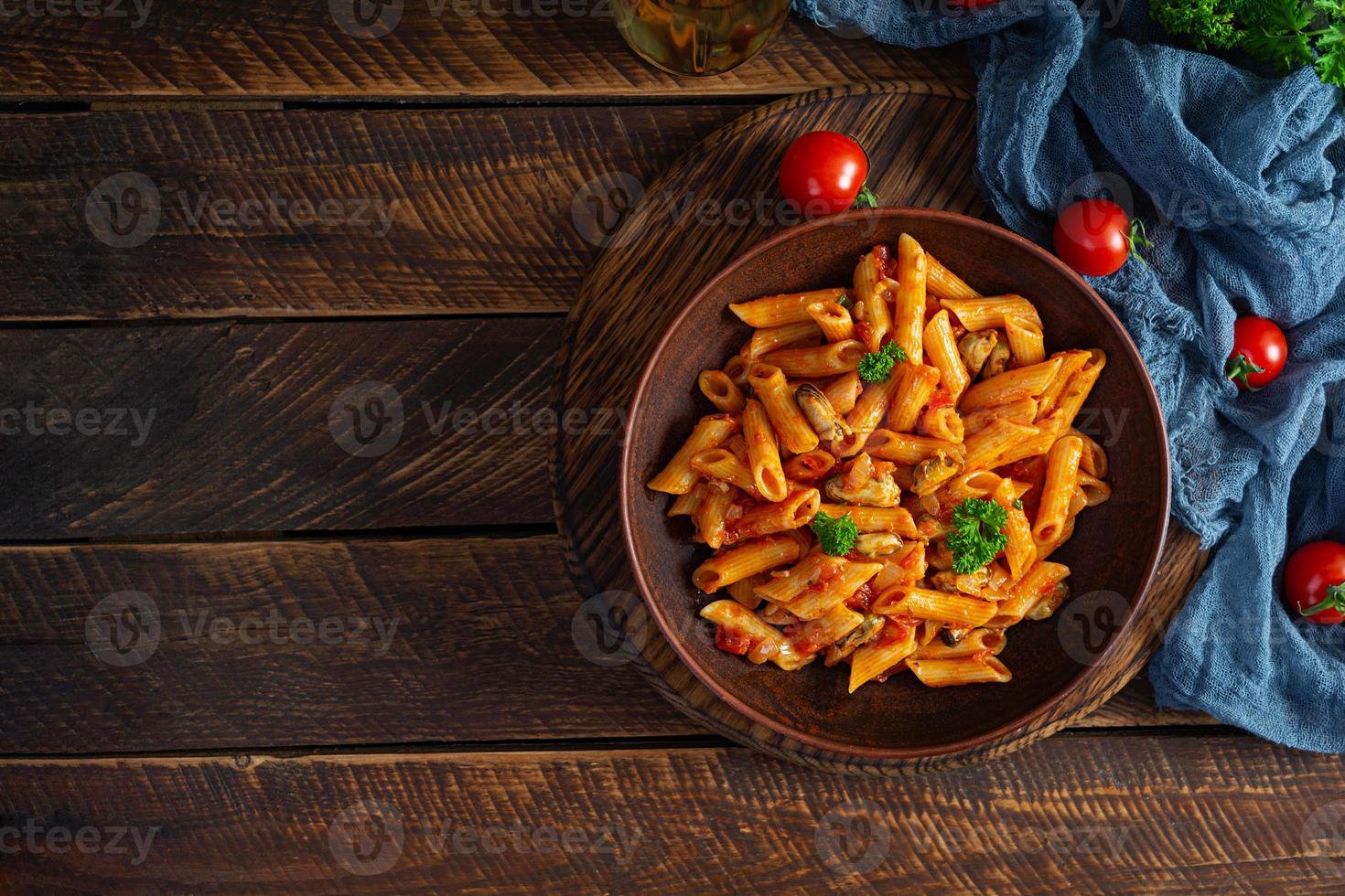 Pasta Penne in Marinara-Sauce mit Muscheln, Zwiebeln und Petersilie. Klassische italienische Pasta Penne. Ansicht von oben foto
