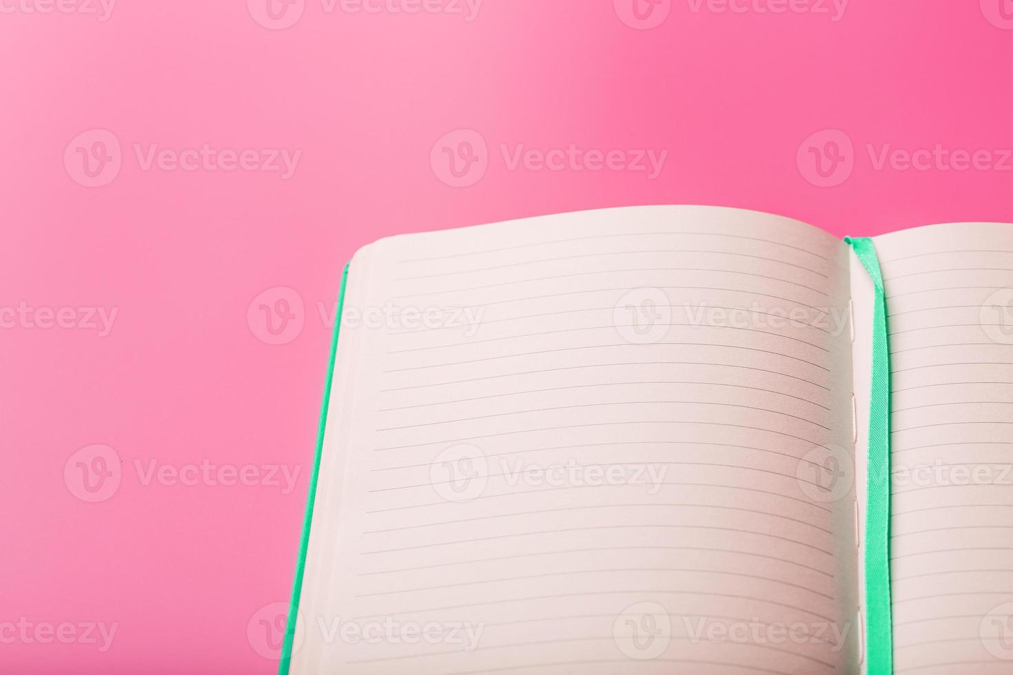 Öffnen Sie einen Laptop mit leeren Seiten auf einem rosa Hintergrund. Draufsicht, Kopierbereich foto