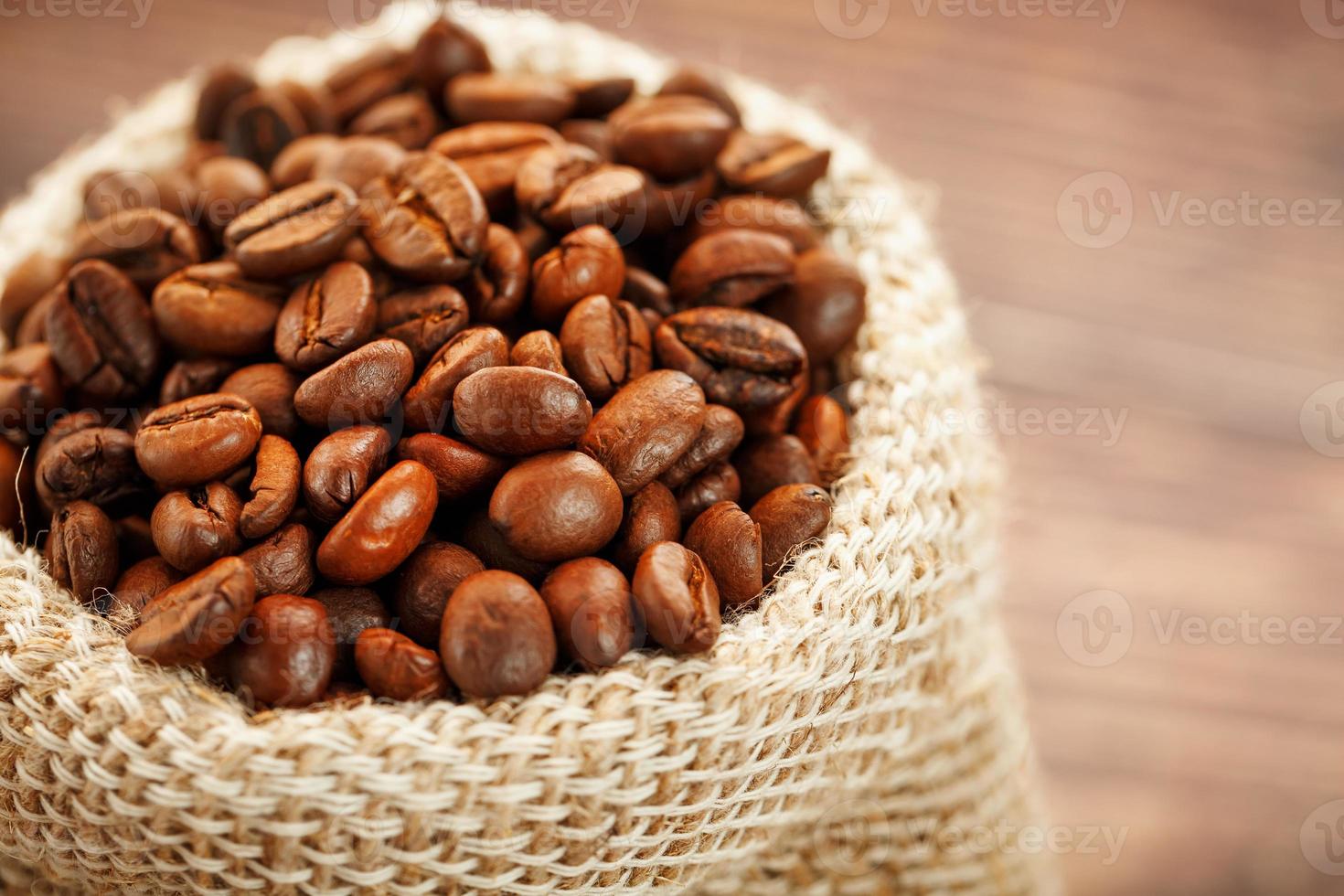 Frisch gerösteter aromatischer Kaffee in einem Leinensack auf Holzhintergrund. foto