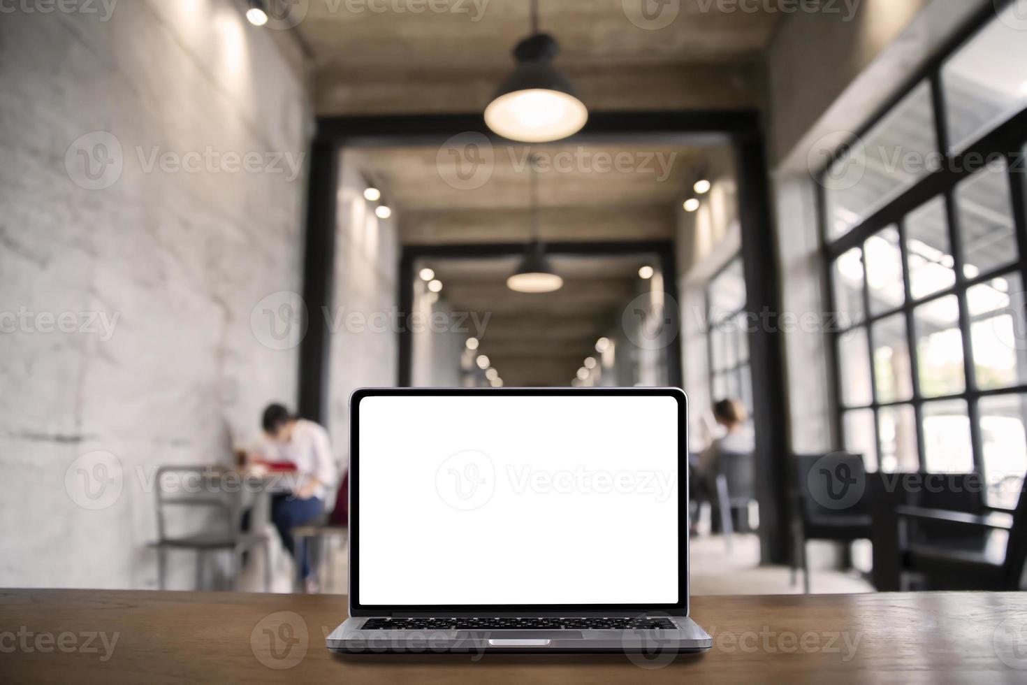 laptop-computer mit leerem weißem bildschirm auf tisch mit modernem arbeitsplatzhintergrund, soziales distanzierungskonzept foto