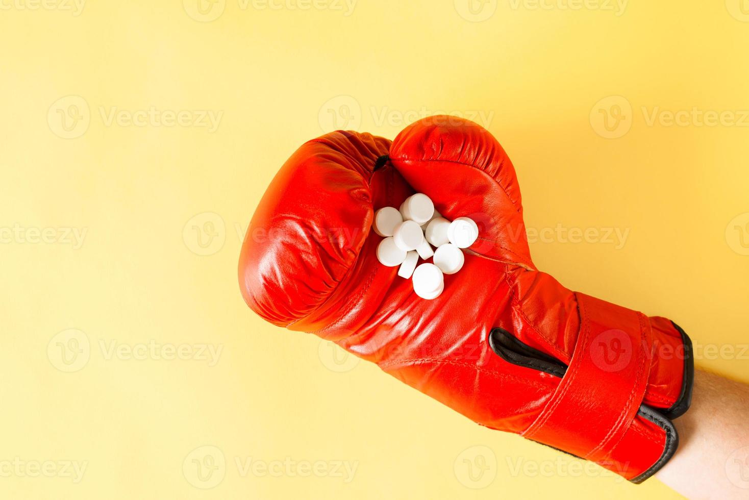 Hand im Boxhandschuh mit Haufen Pillen, Nahaufnahme. gelber hintergrund, draufsicht. foto