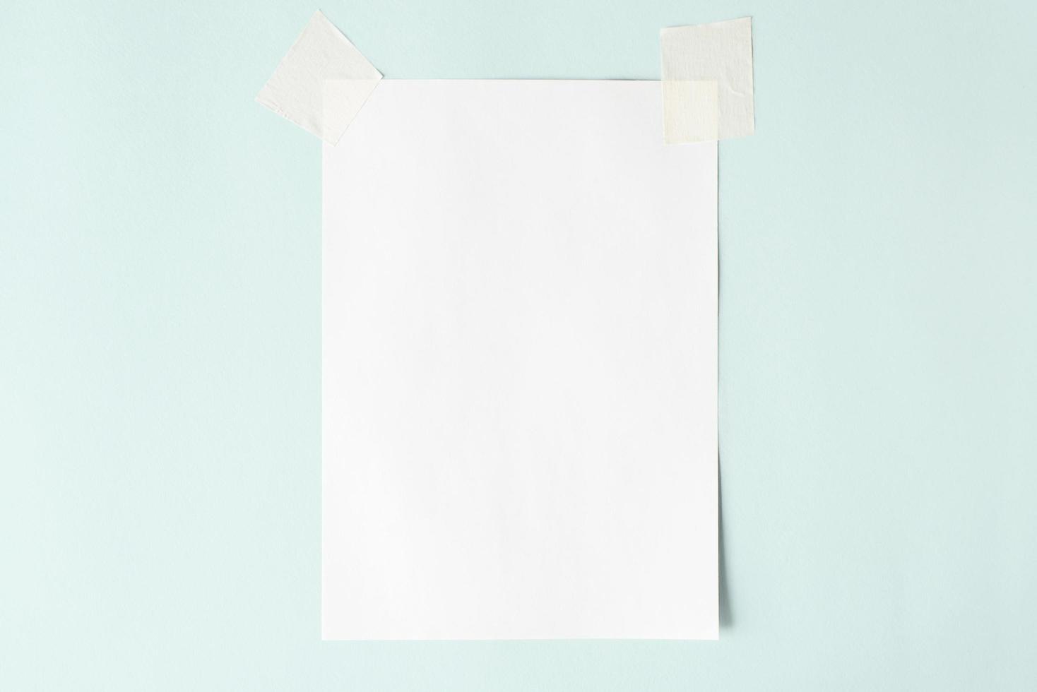 weißes Blatt auf Klebeband, Layout. leeres blatt papier auf pastellblauem hintergrund, kopierraum foto