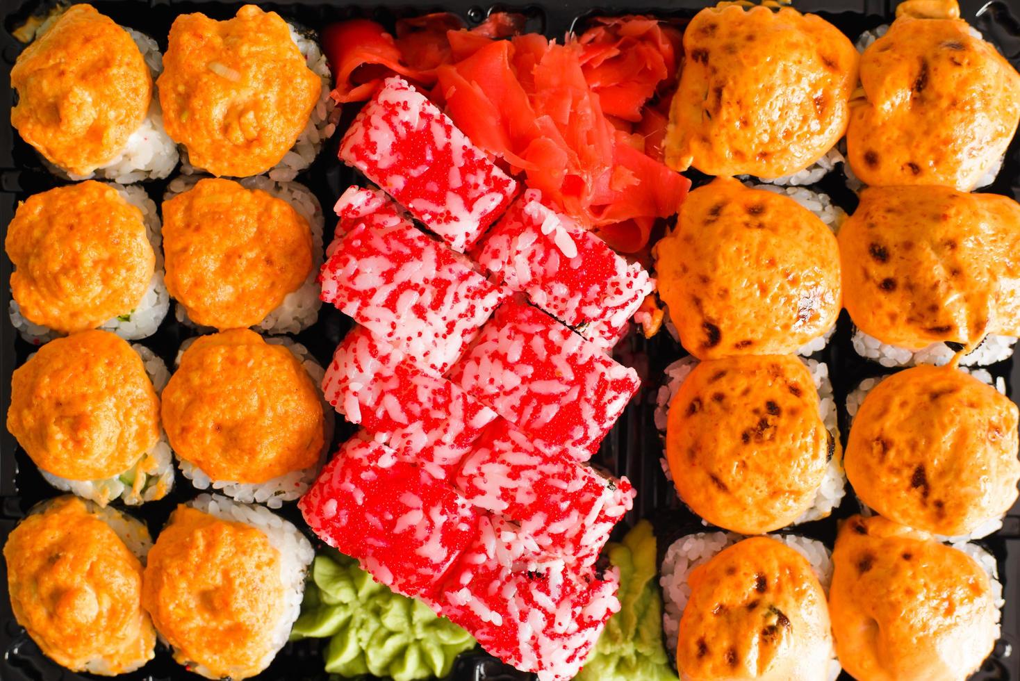 japanisches traditionelles essen sushi und brötchen, nahaufnahme. Satz gebackene und kalifornische Brötchen in einem Plastikbehälter, Ansicht von oben foto