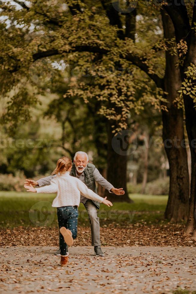 Großvater verbringt am Herbsttag Zeit mit seiner Enkelin im Park foto