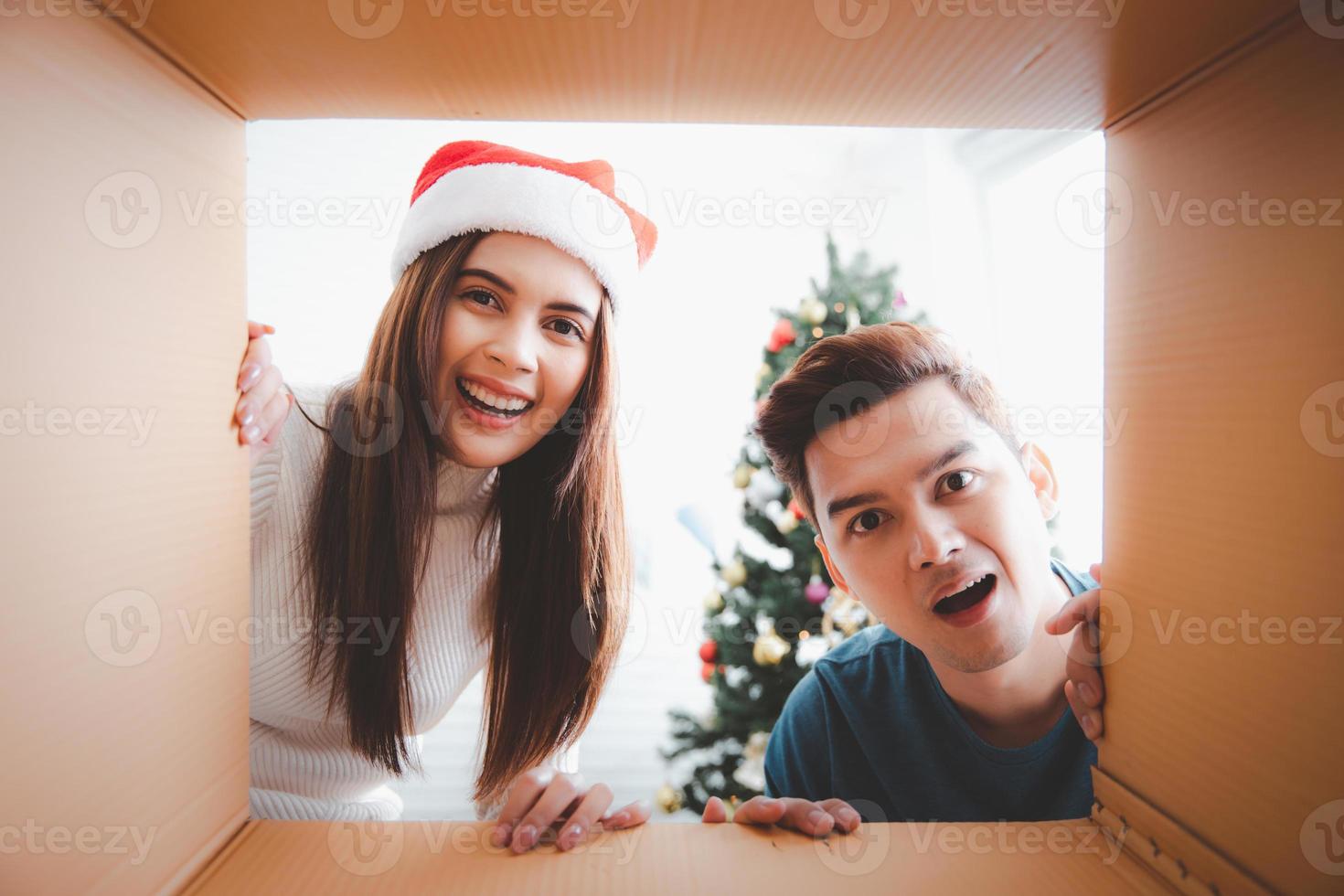 junges Paar, das ein Weihnachtsgeschenk öffnet und in die Schachtel schaut, Blick von der Innenseite der Schachtel foto