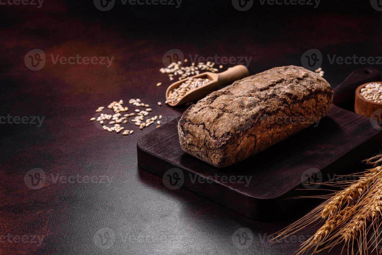 Ein Laib Schwarzbrot mit Getreidekörnern auf einem Holzschneidebrett foto