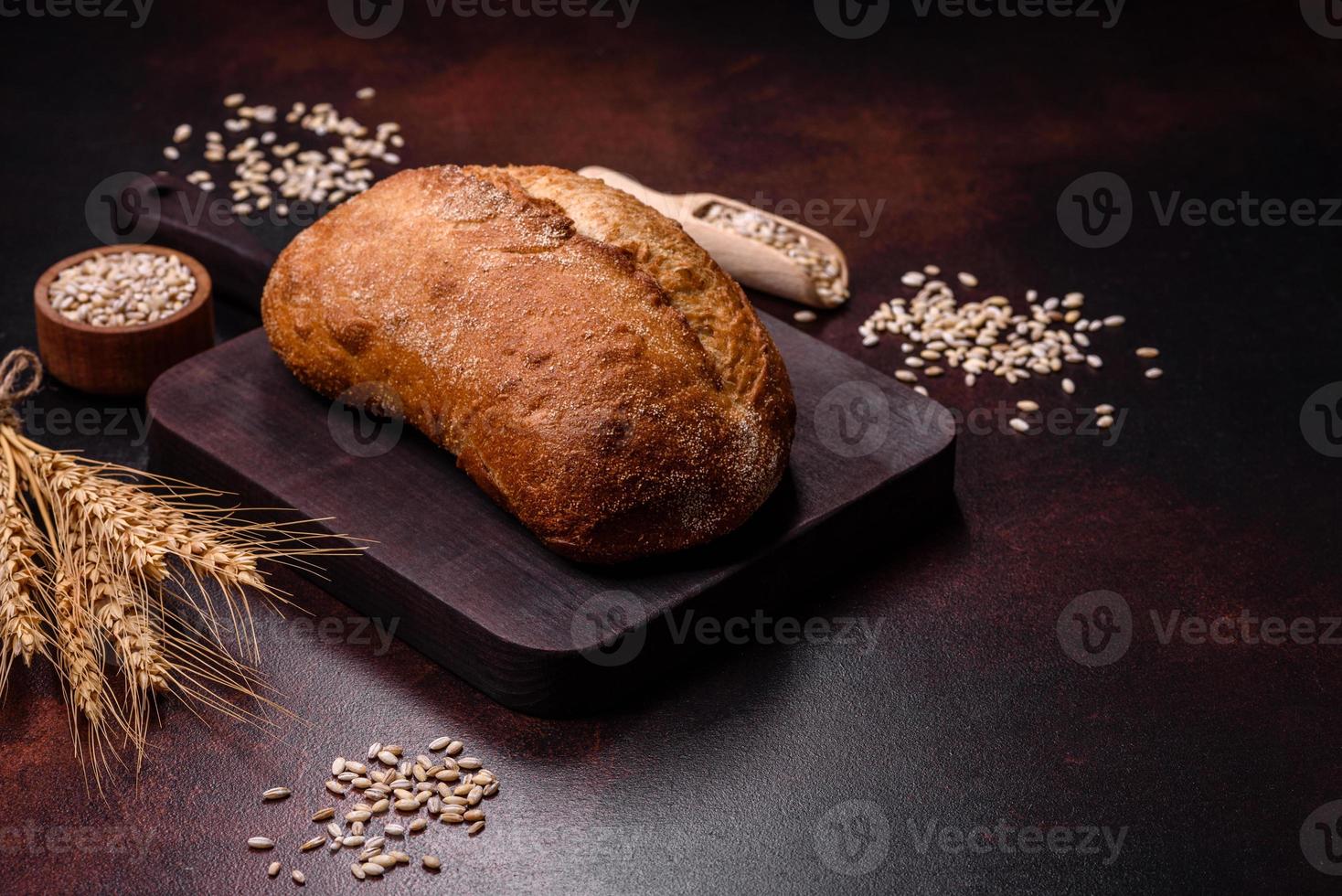 Ein Laib Schwarzbrot mit Getreidekörnern auf einem Holzschneidebrett foto