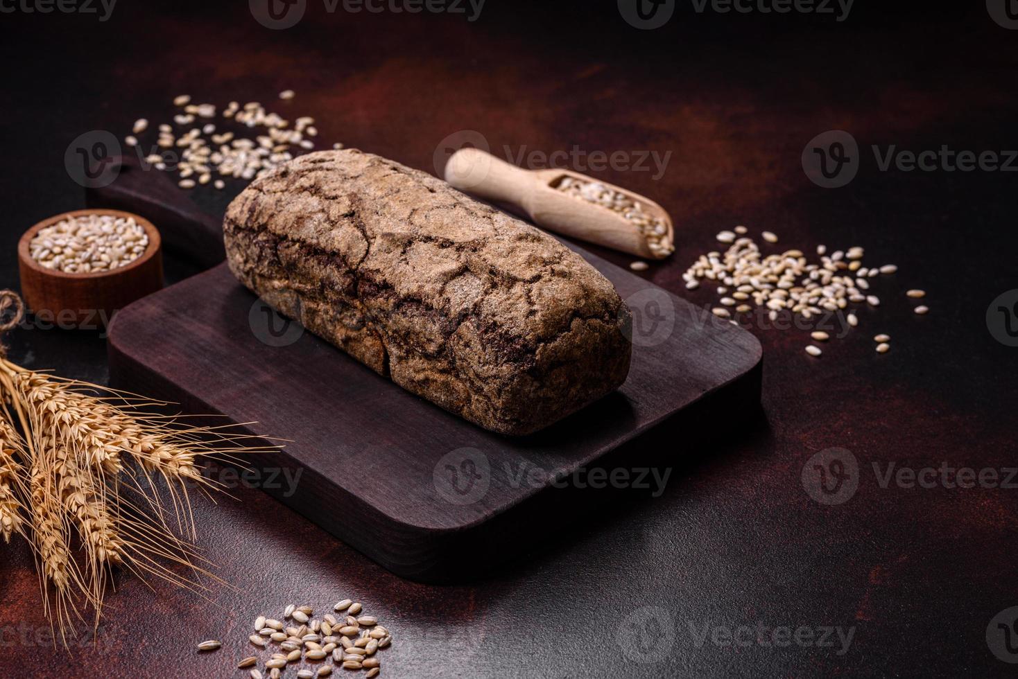 Ein Laib Schwarzbrot mit Getreidekörnern auf einem Holzschneidebrett foto