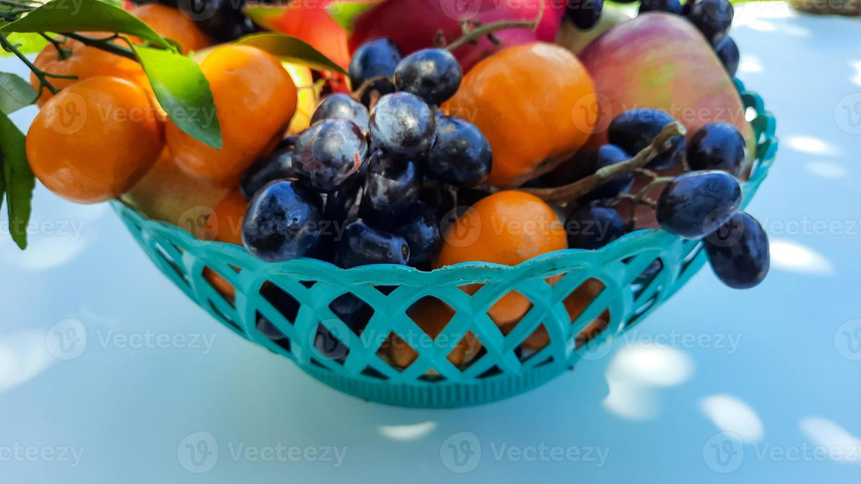 Nahaufnahme, tropische Drachenfrucht Orangen, Birnen, Trauben in einem grünen Korb auf weißem Hintergrund 03 foto