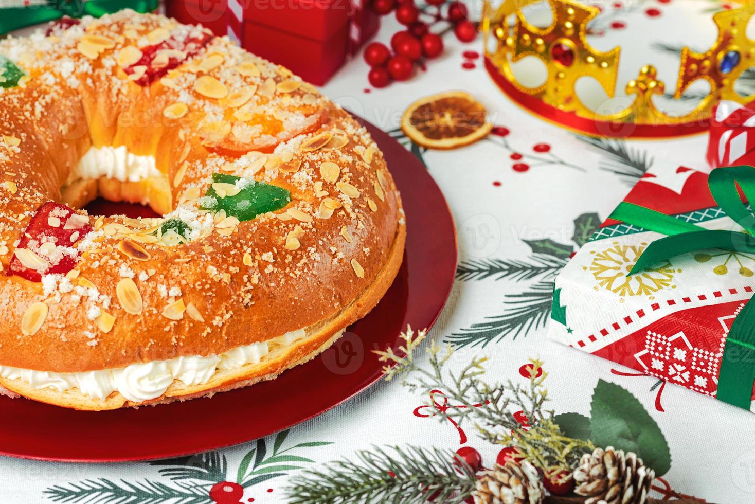 roscon de reyes mit creme und weihnachtsschmuck auf einem roten teller. königstag konzept spanischer dreikönigskuchen.typisches spanisches dessert zu weihnachten foto