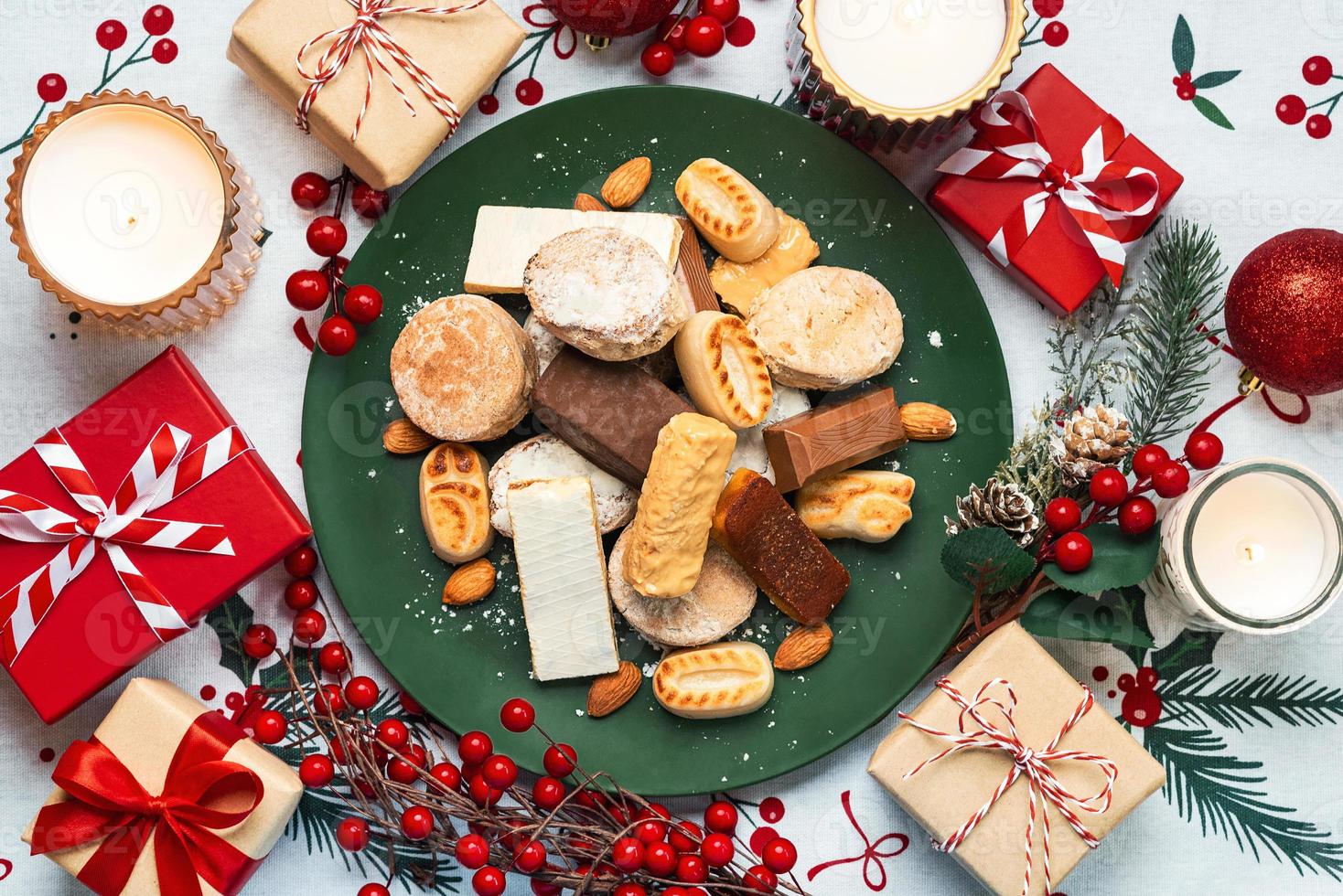 Draufsicht auf Nougat-Weihnachtsbonbon, Mantecados und Polvorones mit Weihnachtsschmuck auf einem Teller. auswahl an weihnachtssüßigkeiten, die typisch für spanien sind foto