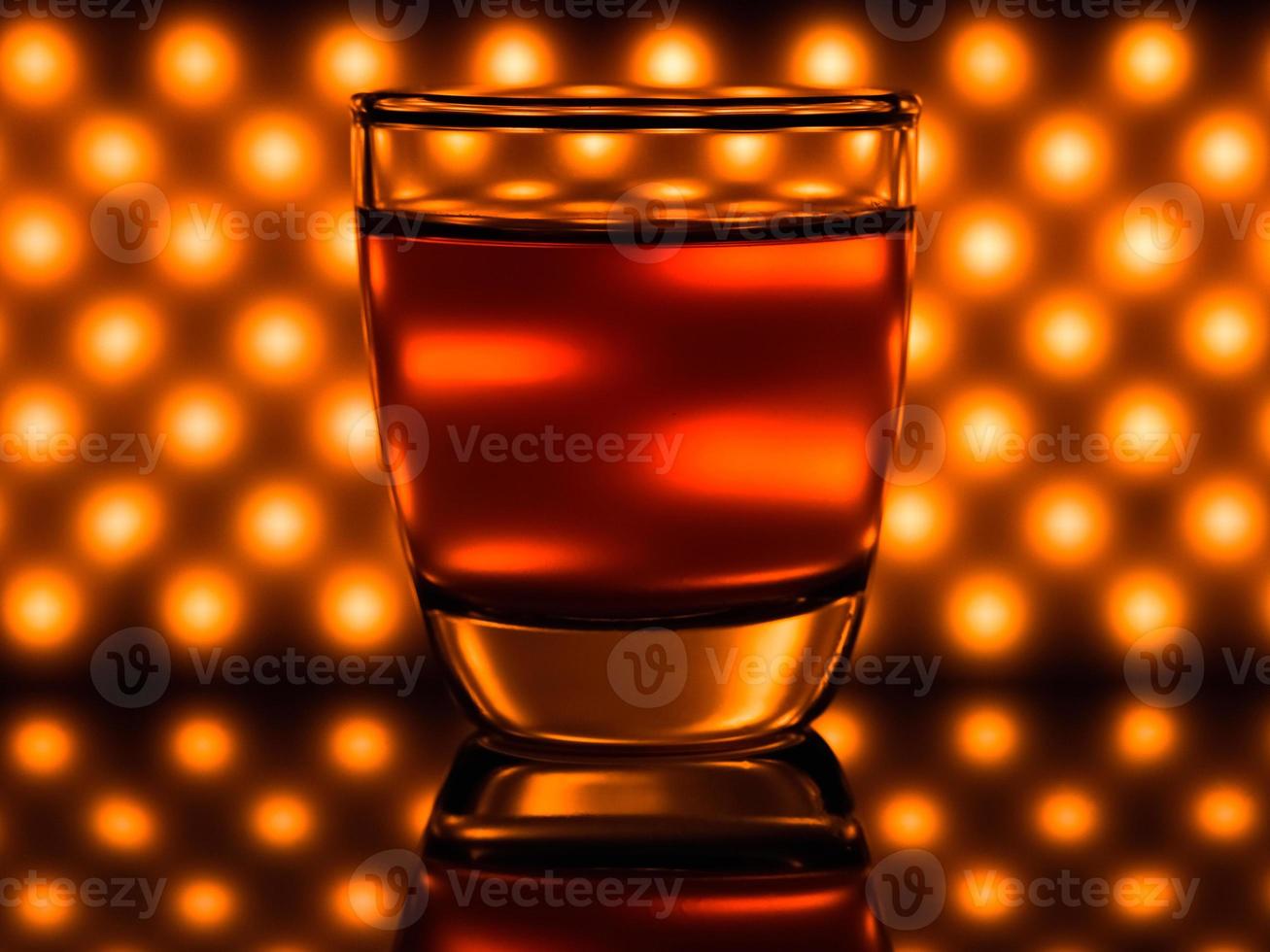 Glas Whiskey und orangefarbene Lichter im Hintergrund foto