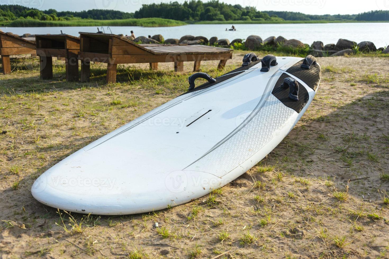 surfbrett liegt auf dem sand am strand am ufer des sees, meer, wassersport, aktiver lebensstil, urlaub, wärme, ruhe foto