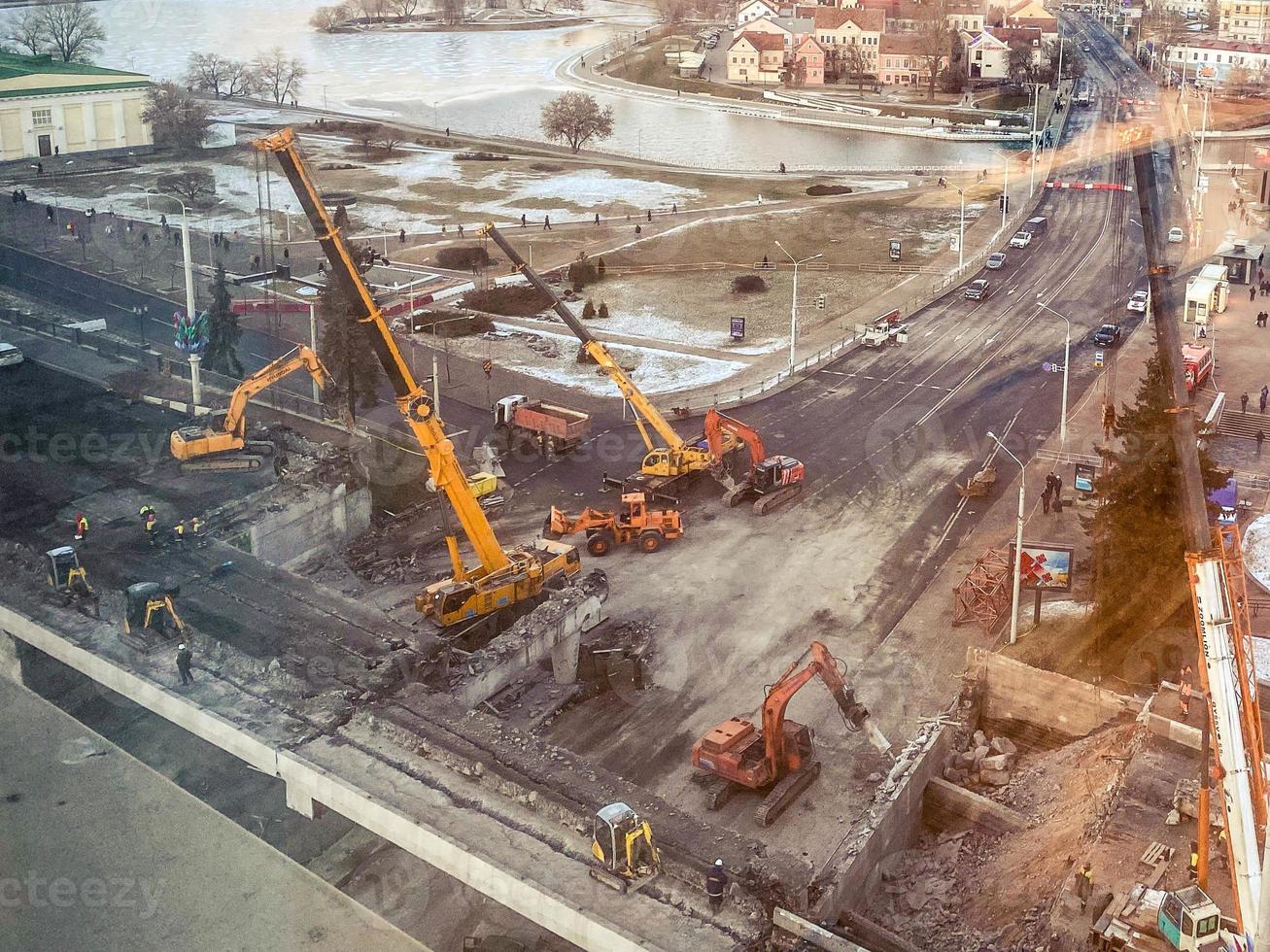 Bau einer Brücke in der Innenstadt. Bau einer neuen Überführung auf einem eingezäunten Straßenabschnitt. Blick aus der Höhe auf eine Großbaustelle foto