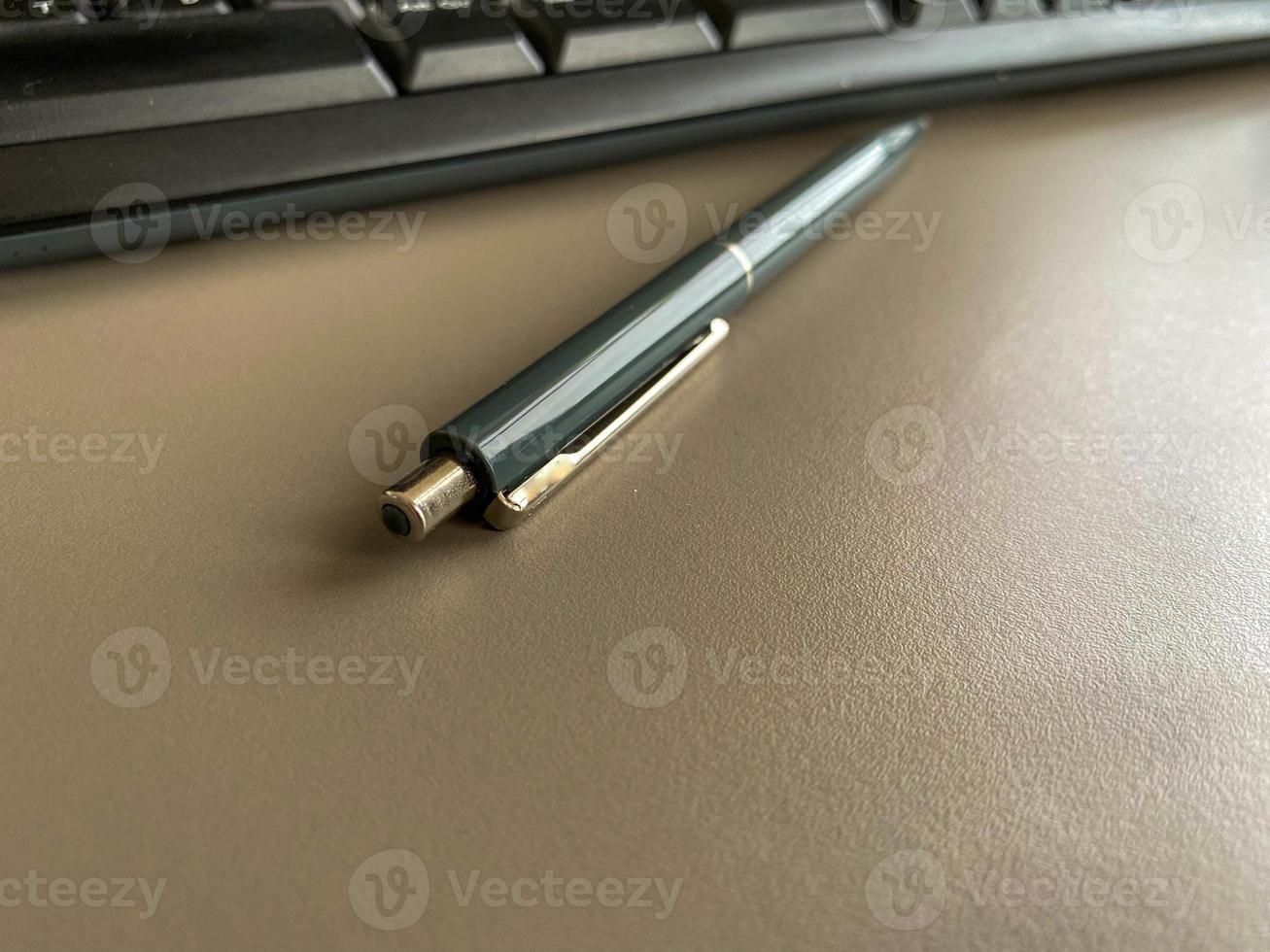 Automatischer grüner Kugelschreiber zum Schreiben auf dem Schreibtisch mit Computertastatur. geschäftliche Arbeit foto