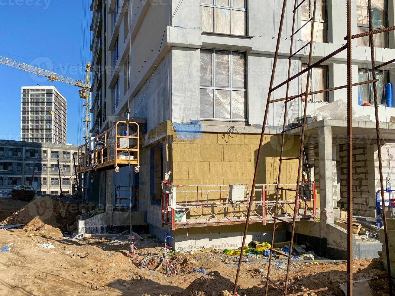 Fertigstellung der Fassade eines monolithischen Gebäudes aus Beton- und Gassilikatblöcken mit Mineralwolldämmung während des Baus und der Renovierung des Hauses mit modernen Materialien foto