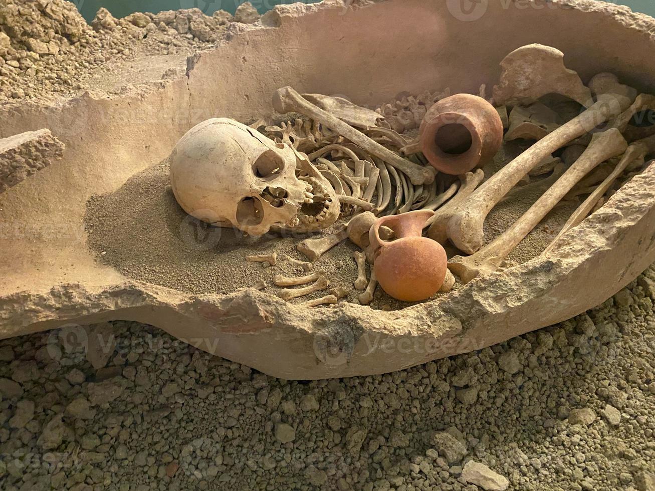 Menschliche Schädel- und Knochenreste, die auf Felsen liegen foto