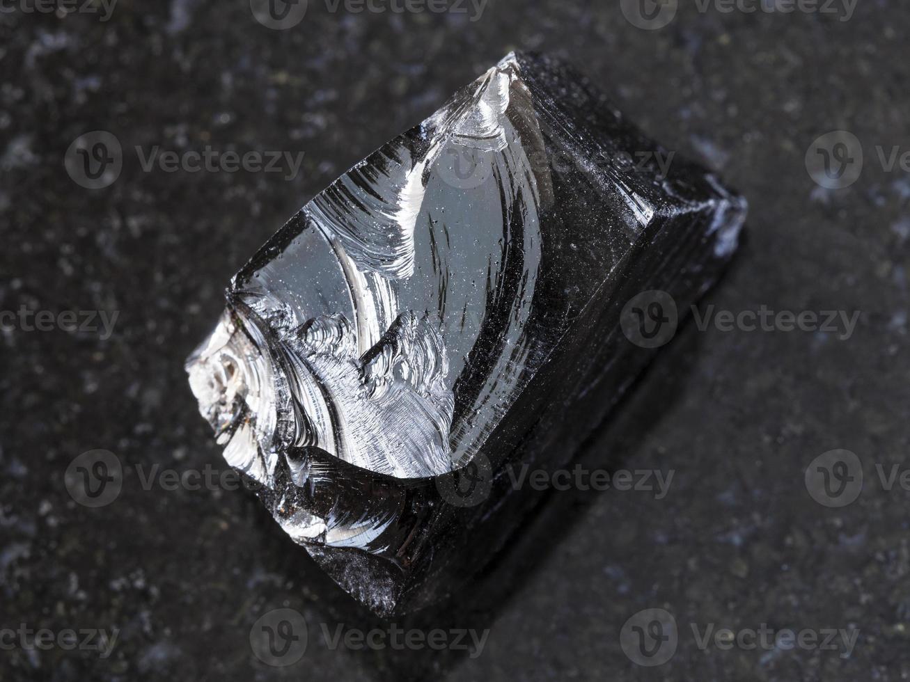 Stück rohes Obsidian-Vulkanglas auf Dunkelheit foto