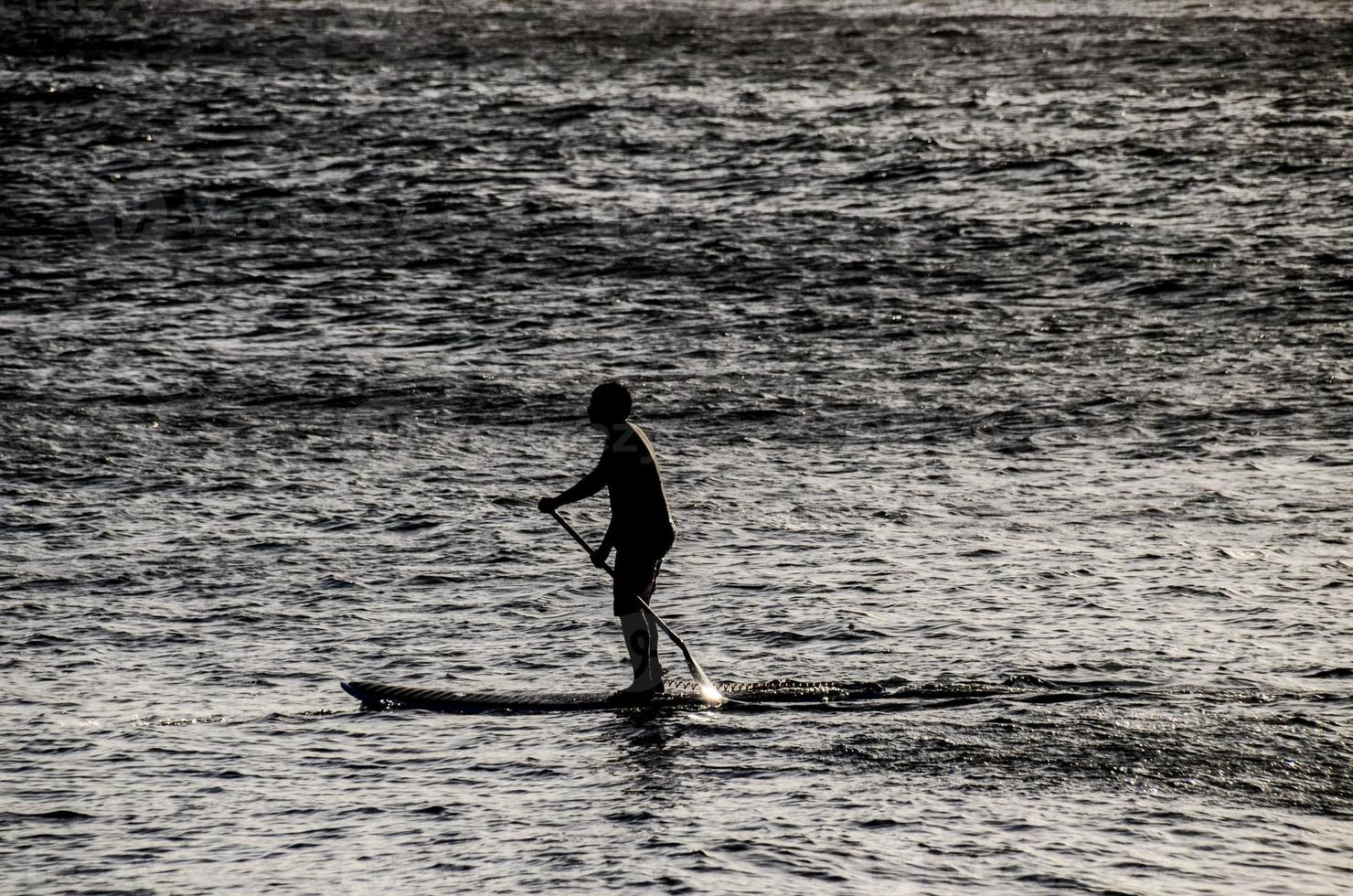 Silhouette eines Mannes im Paddelbrett foto