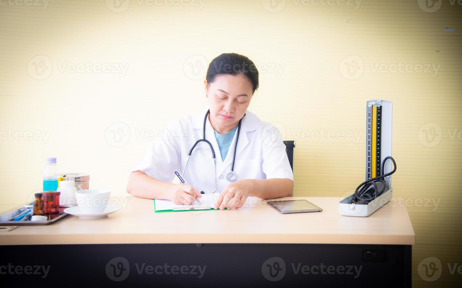 Ärztin mit medizinischen Geräten überprüft die Gesundheit des Patienten und nimmt das Weißbuch im Krankenhaus zur Kenntnis, das das Gesundheitsgeschäft ist foto