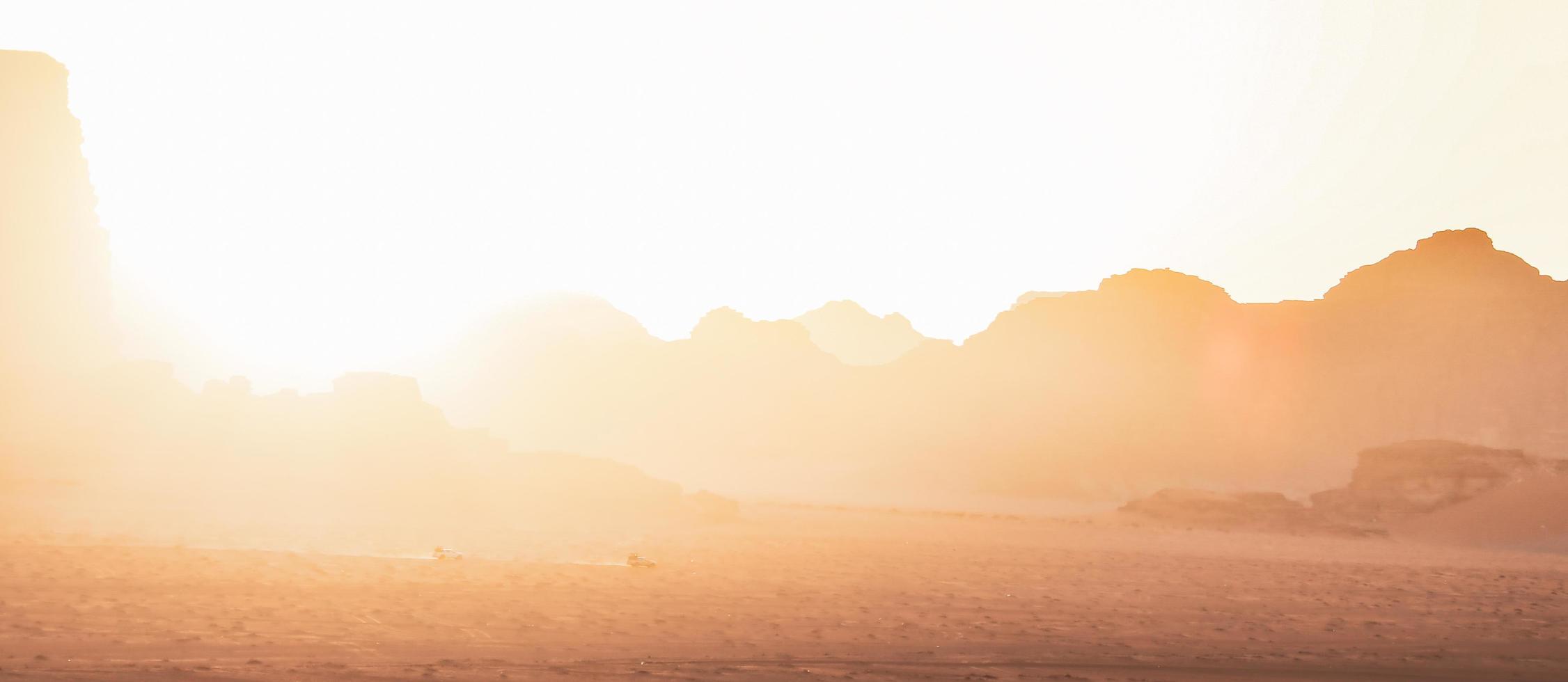 wadi rum wüstenlandschaft mit einer reihe von allradfahrzeugen fahren vom aussichtspunkt des sonnenuntergangs auf einer organisierten sonnenuntergangstour in jordanien foto