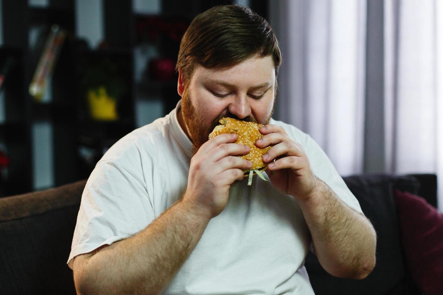 großer Mann, der einen Burger isst foto